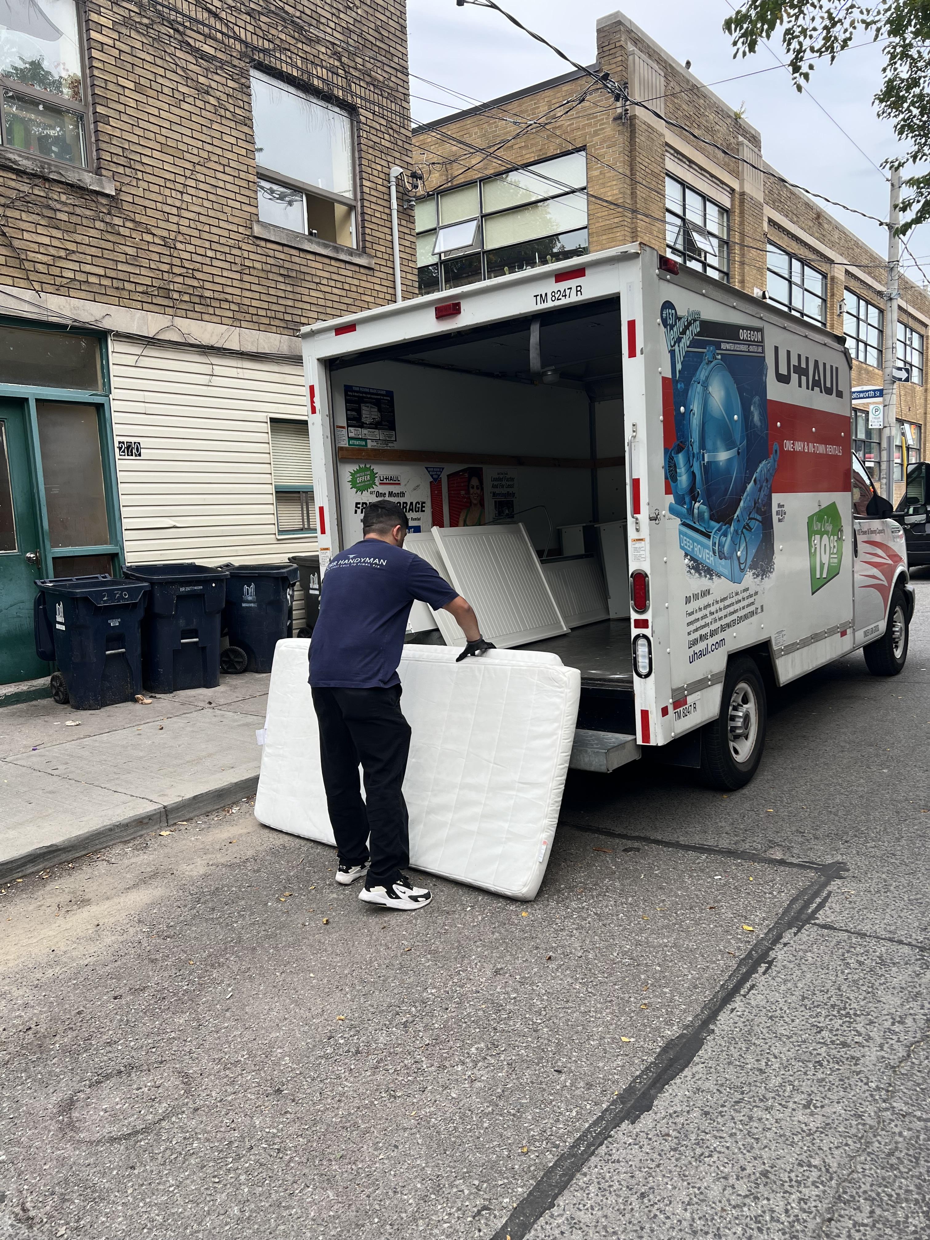 Worker loading a mattress into a truck during a rental cleanout
